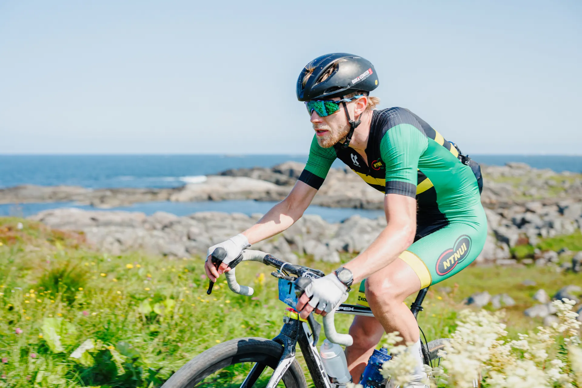 Wielrenner op een gravelfiets langs een rotsachtige kust, de zee op de achtergrond